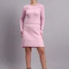 Woman wearing light pink ribbed knit winter dress with scallop hem and peter pan collar, styled with ankle boots.