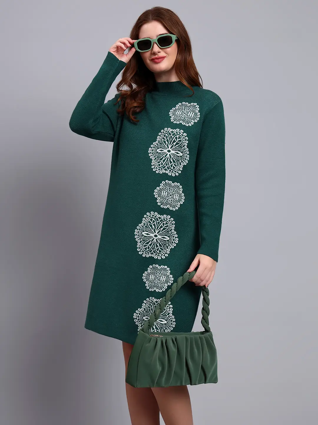 Woman in green knit winter dress with vertical white geometric embroidery, high neck, and full sleeves.