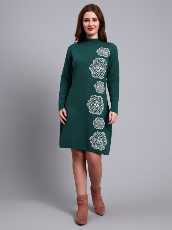 Woman in green knit winter dress with vertical white geometric embroidery, high neck, and full sleeves.
