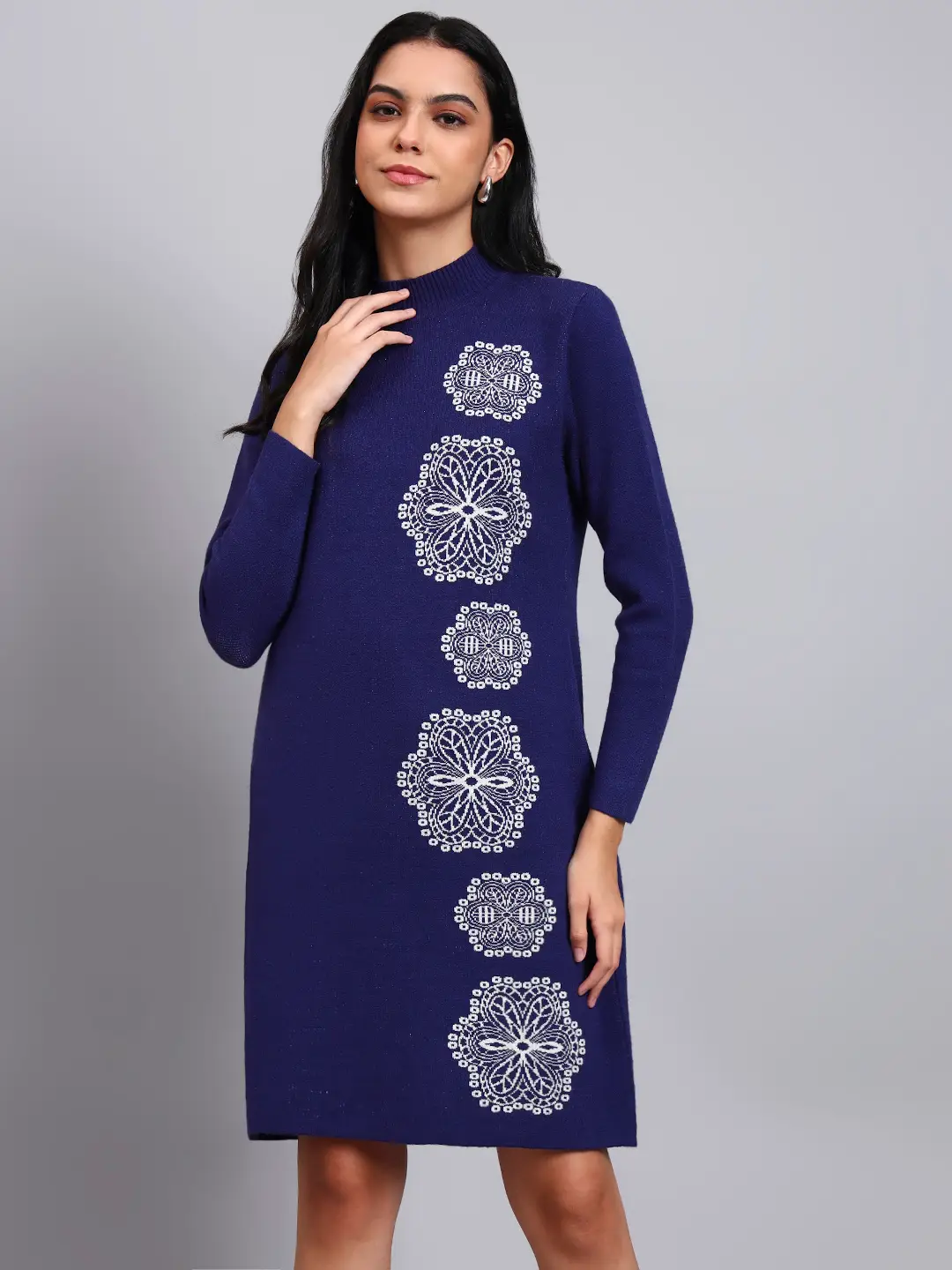 Woman in navy blue knit winter dress with vertical white geometric embroidery, high neck, and long sleeves.