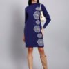 Woman in navy blue knit winter dress with vertical white geometric embroidery, high neck, and long sleeves.