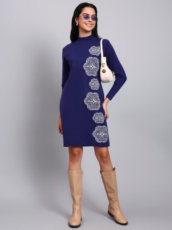 Woman in navy blue knit winter dress with vertical white geometric embroidery, high neck, and long sleeves.