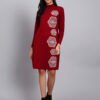 Woman in wine red knit winter dress with vertical white geometric embroidery, high ribbed neck, and full sleeves.