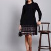 Woman in black knit winter dress with pink and white patterned hem, button front, and long sleeves Woman in black knit winter dress with pink and white patterned hem, button front, and long sleeves