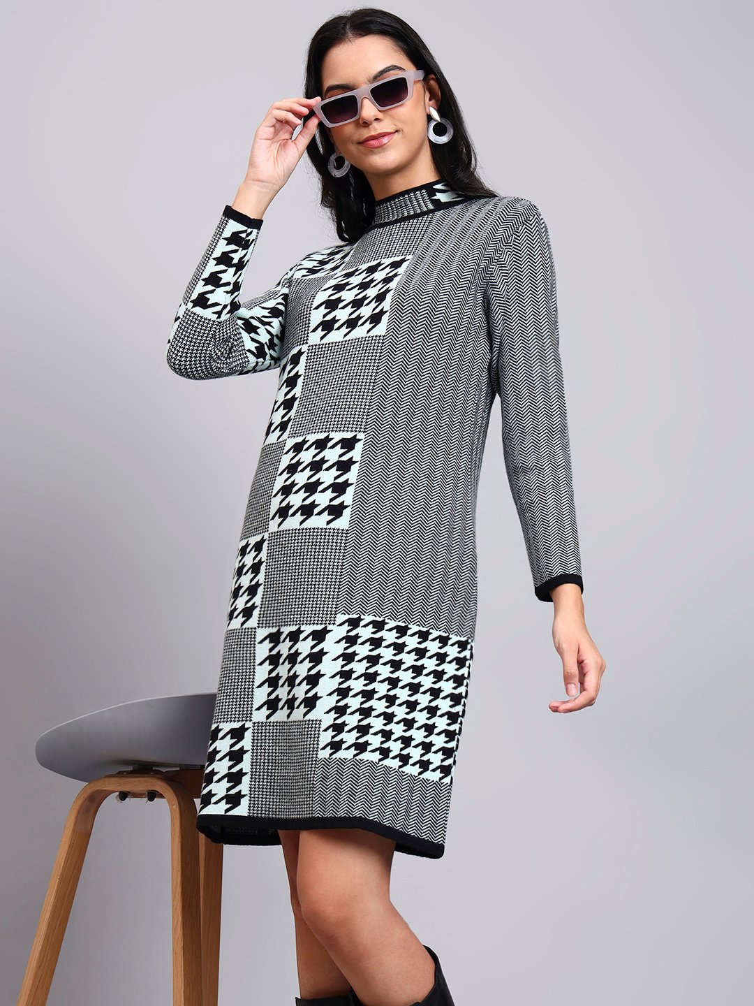 Woman in dusty sky blue and black patterned knit winter dress with houndstooth, high ribbed neck, and long sleeves