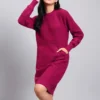 Woman in rani pink textured knit midi winter dress with long sleeves, round neck, and front pocket