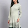 Woman wearing pista green knit winter dress with green and navy patterned hem, button front, and long sleeves Woman wearing pista green knit winter dress with green and navy patterned hem, button front, and long sleeves