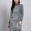 Woman in dusty sky blue and black patterned knit winter dress with houndstooth, high ribbed neck, and long sleeves