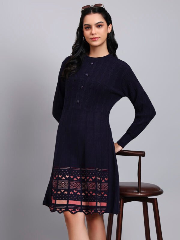 Woman wearing navy knit winter dress with pastel pink patterned hem, button-front bodice, and long sleeves