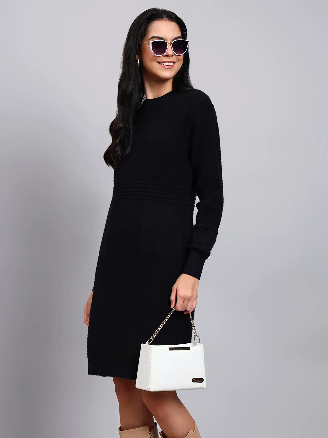 Woman in black textured knit winter dress with round neck, long sleeves, and front pocket detail.
